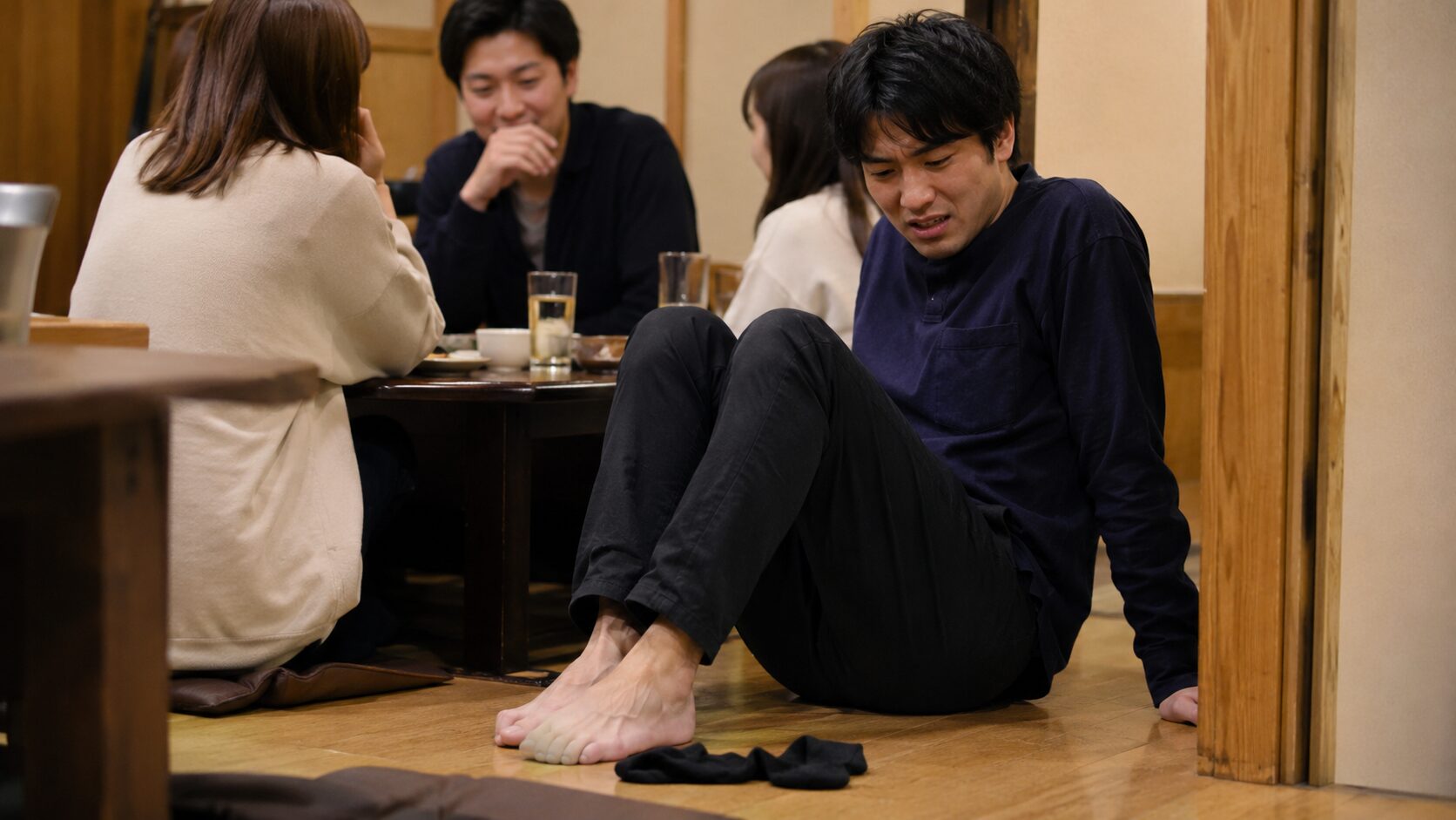 居酒屋座敷で靴を脱ぎ足の臭いに気づき動揺する20代男性
