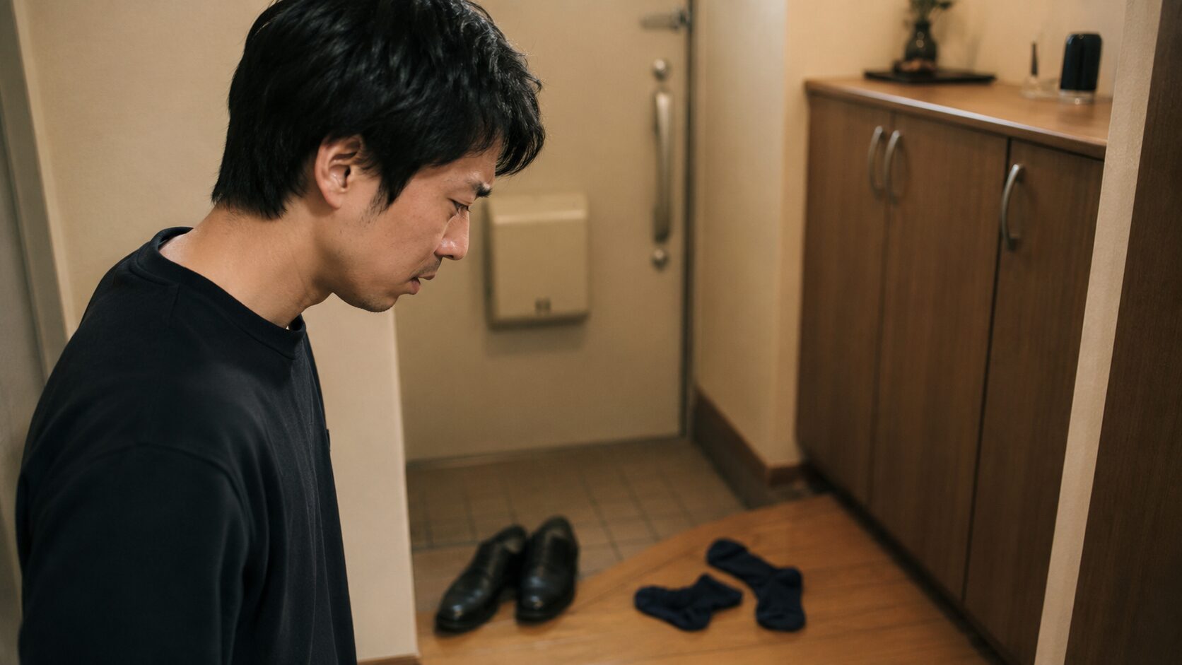 靴を脱いだ瞬間に足の臭いに気付き眉をひそめる30代男性