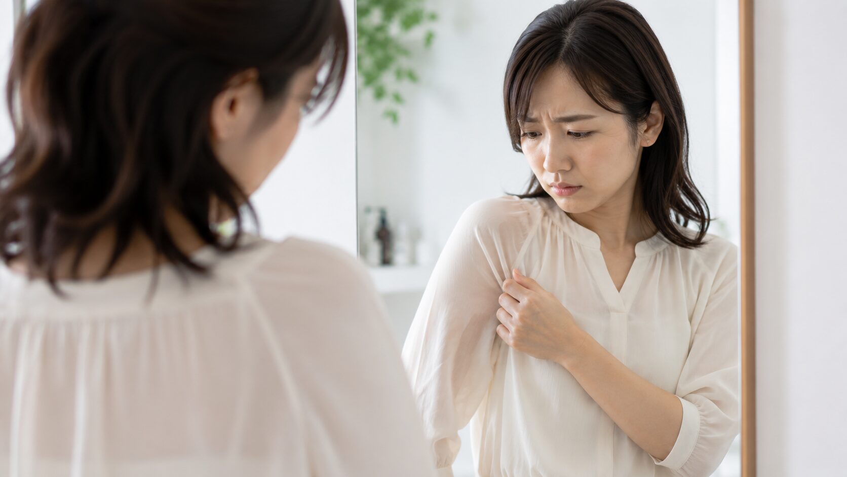 脇汗が少ないのに臭うと悩む女性が鏡の前で確認する様子