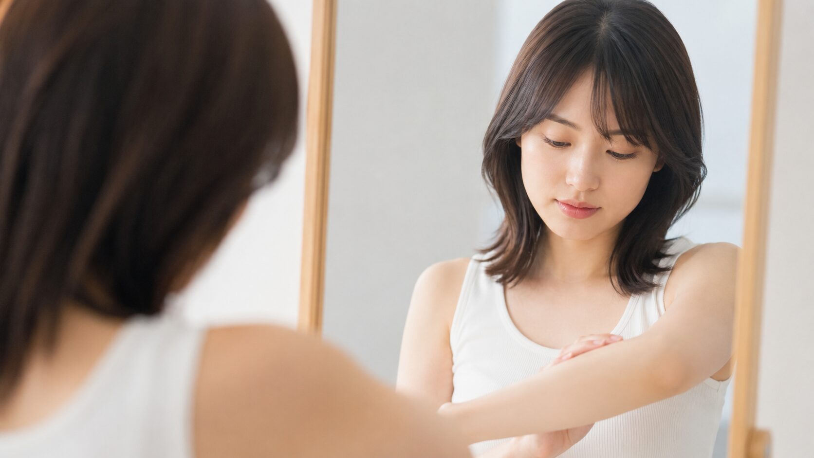 社会人が脱毛をいつから始めるか鏡の前で悩む20代女性